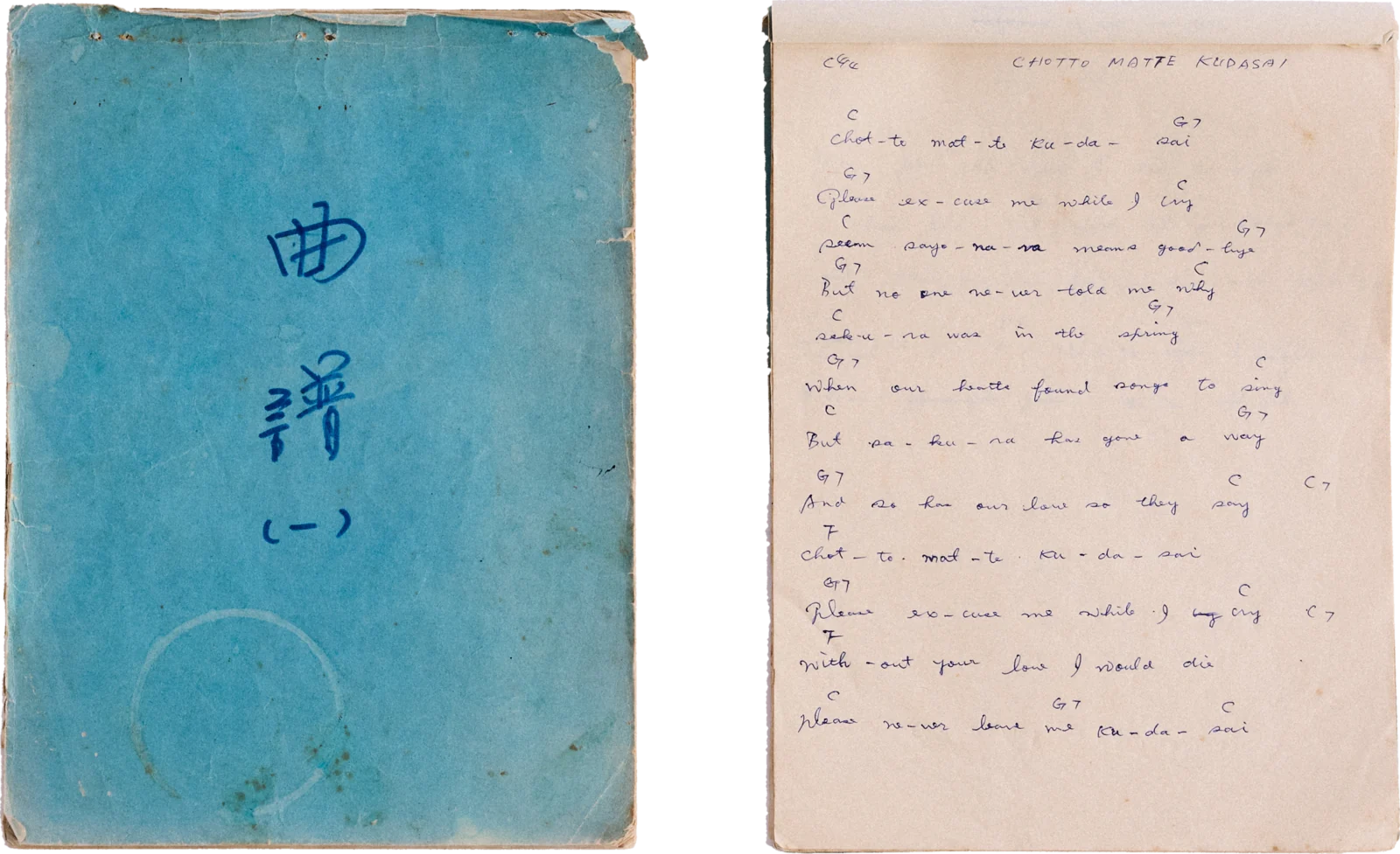 A worn blue songbook marked 曲譜 (一), beside a handwritten page of lyrics